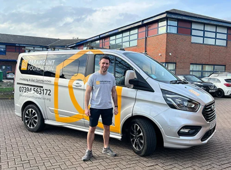 Paramount foundation minibus and a volunteer outside Paramount's office