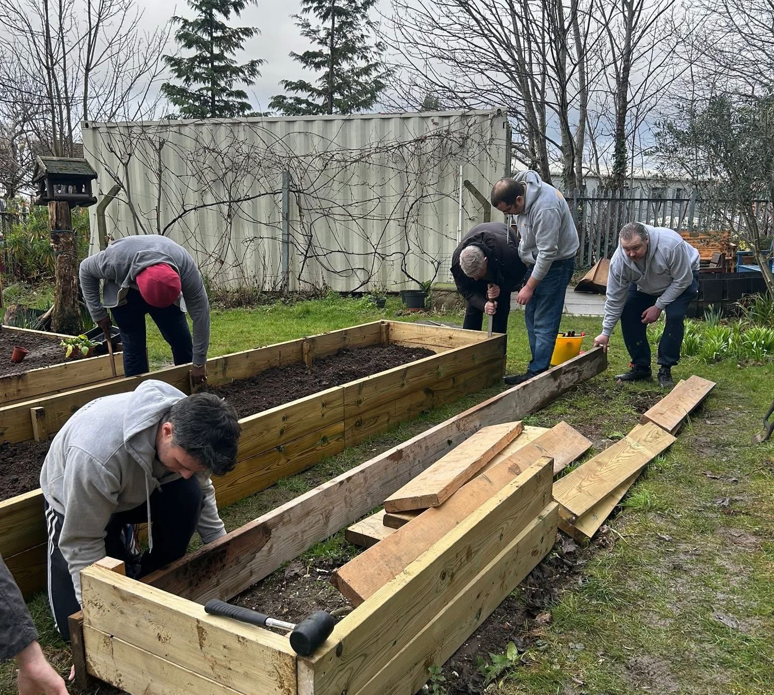 Volunteers building wooden raised planters in a community vegetable garden